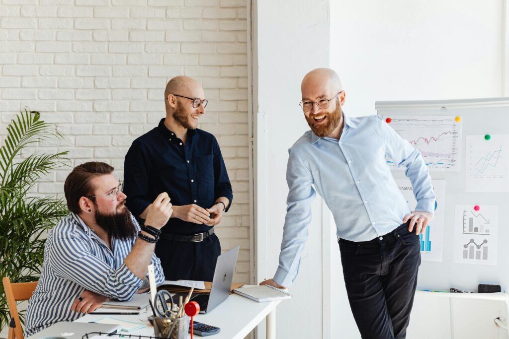 Three male colleagues engaged in a collaborative business meeting in a modern office.